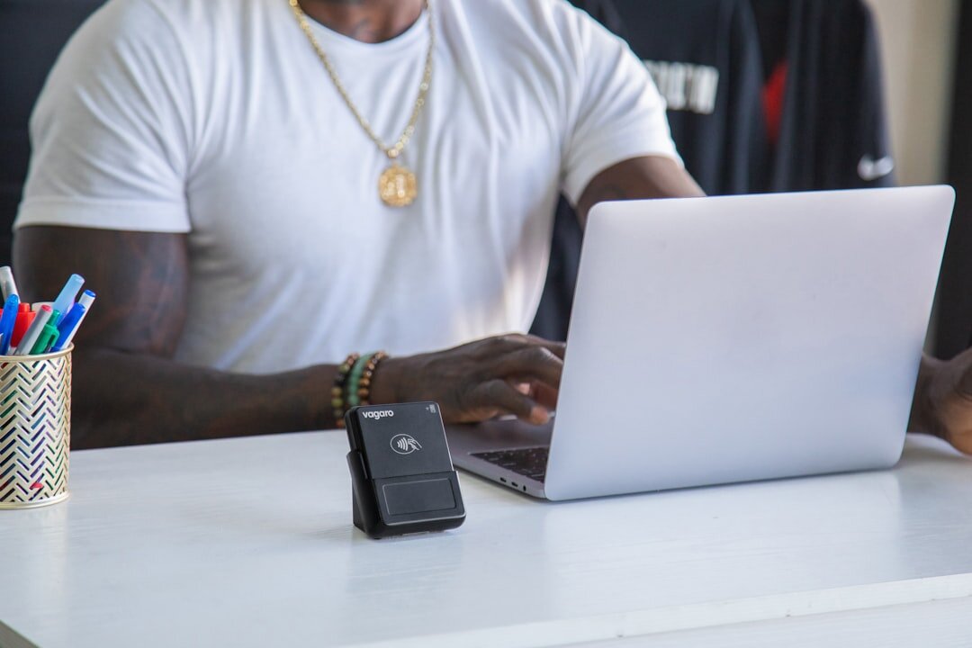 Hands typing on a laptop with notes on a desk